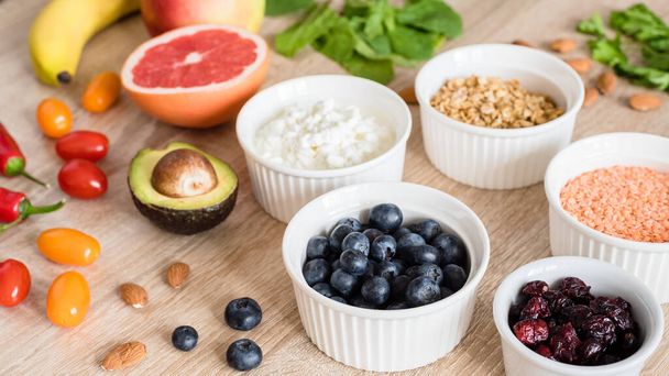 Healthy food concept. Cottage cheese, fruits, vegetables, leaf vegetables, berries, dried fruits and nuts on a wooden table. clean food - Photo, Image