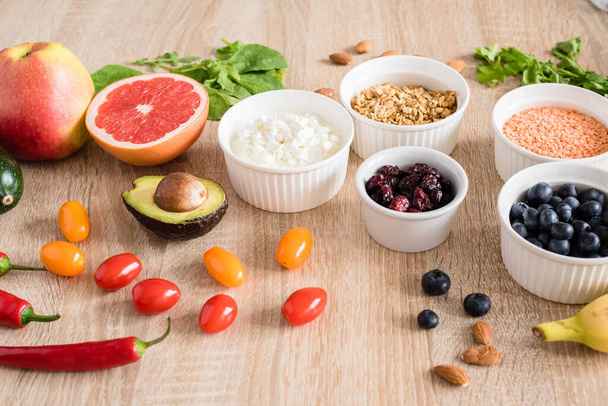 Healthy food concept. Cottage cheese, fruits, vegetables, leaf vegetables, berries, dried fruits and nuts on a wooden table. clean food - Photo, Image