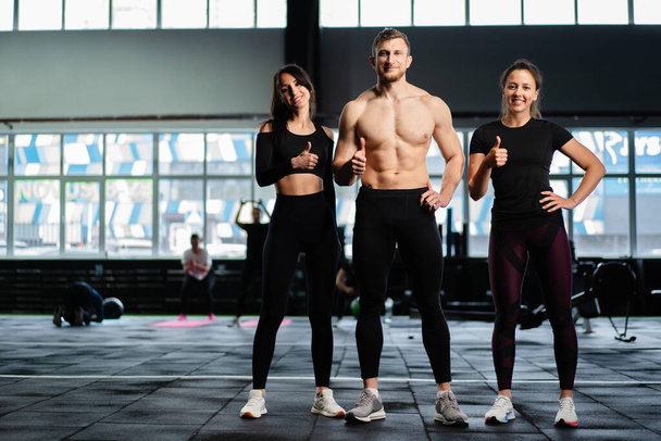 homme caucasien sexy et les femmes dans le train de gymnase dans le club de fitness avec des poids style de vie exercice de bien-être avec joie - Photo, image