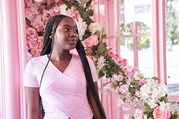 African-American woman with braids against a background of pink flowers. - Foto, afbeelding