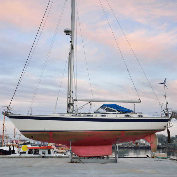 45 ft cruising sailboat standing on land in a yacht marina. Transportation, nautical vessel, repair and service, sailing, sport, recreation. tourism, leisure activity concepts - 写真・画像