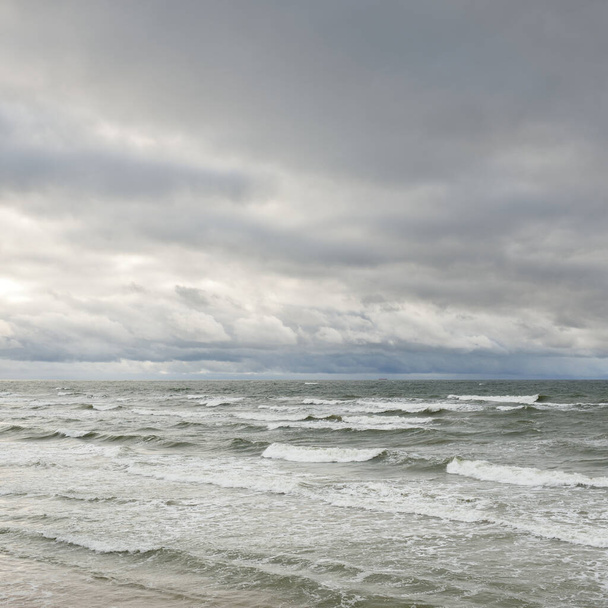 Ostsee während des Sturms. Dramatischer Himmel, dunkle glühende Wolken. Wellen, Wasser plätschert. Idyllische Meereslandschaft. Klimawandel, Natur, unbeständiges Wetter, Ökologie - Foto, Bild