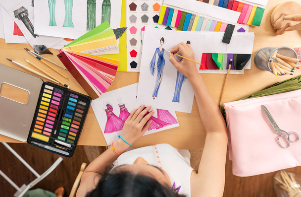 Mooie Aziatische Fashion ontwerper tekening schetsen voor nieuwe collectie op bureau bovenaanzicht. Ontwerper creatieve workshop studio. - Foto, afbeelding