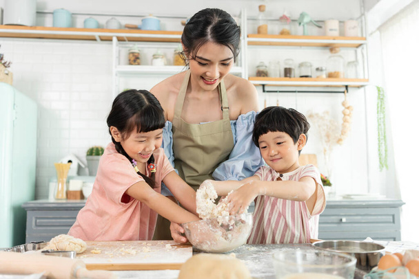 Happy Asian family making preparation tough and bake cookies in kitchen at home. Наслаждайтесь семейной активностью вместе. - Фото, изображение