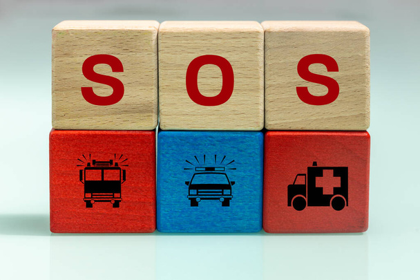 Blocchi in legno con iscrizione SOS e icone dei vigili del fuoco, polizia e ambulanza, concetto di soccorso, servizi di soccorso e problemi sociali - Foto, immagini