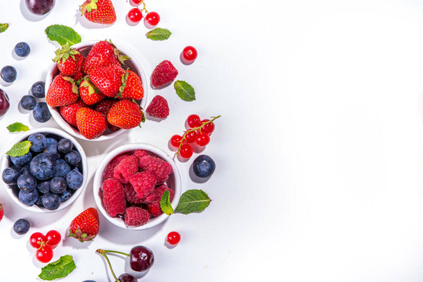 Concept de nourriture vitaminée d'été, ensemble de diverses baies myrtille fraise groseille, plat posé sur fond blanc vue du dessus copier l'espace - Photo, image