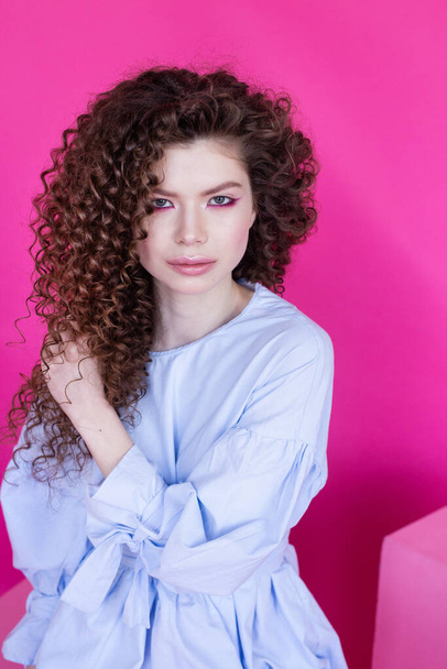 Fashion model girl with curly wavy shiny healthy hair on pink background Hair care bright makeup - Fotografie, Obrázek