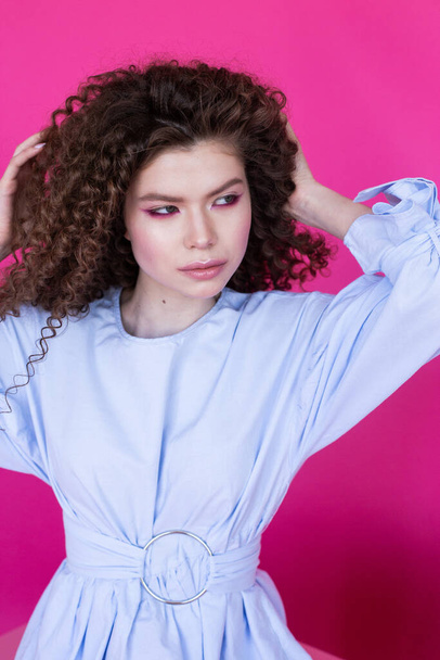 Moda modelo menina com encaracolado ondulado brilhante cabelo saudável no fundo rosa Cuidados com o cabelo maquiagem brilhante - Foto, Imagem