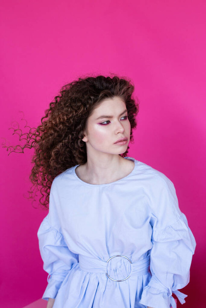 Chica modelo de moda con rizado ondulado pelo sano brillante sobre fondo rosa Cuidado del cabello maquillaje brillante - Foto, Imagen