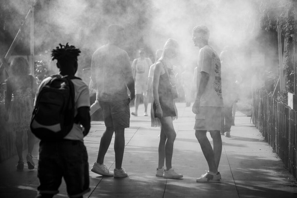 Strasbourg - France - 18 June 2022 - Portrait of people walking in urban park in sprayer installation in black and white - Foto, afbeelding