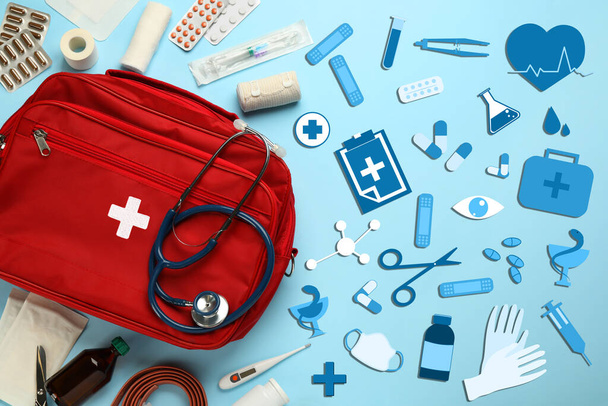 First aid kit and different images on light blue background, flat lay - Foto, Imagen