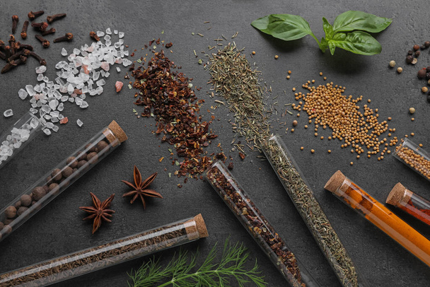 Flat lay composition with various spices, test tubes and fresh herbs on grey background - Photo, image