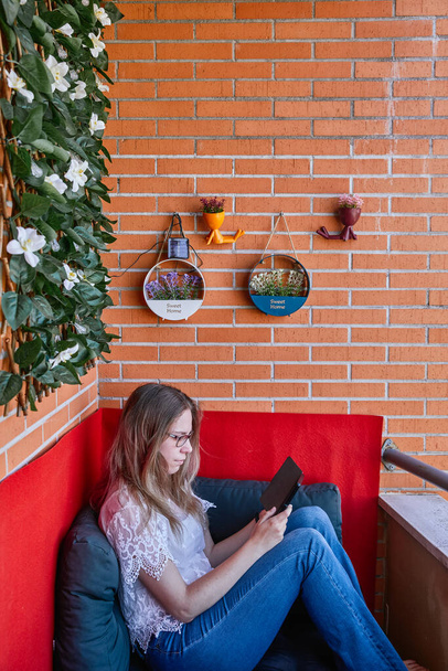 Nuori nainen lukee hänen eBook terassilla kotiinsa - Valokuva, kuva