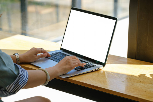 Uma mulher usando um laptop de computador com uma tela branca em branco. O espaço em branco na tela branca pode ser usado para escrever uma mensagem ou colocar uma imagem. - Foto, Imagem