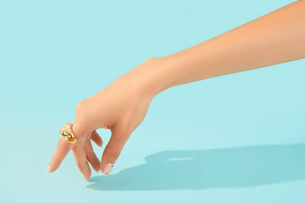 Bela mão de mulheres tratada com anel na moda em fundo azul. Verão de moda conceito de venda de compras. - Foto, Imagem