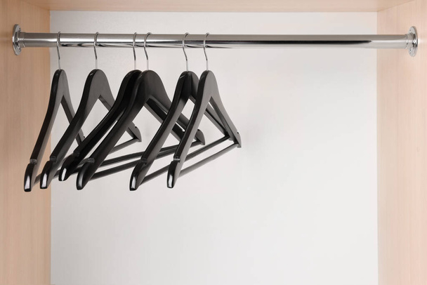 Set of black clothes hangers on wardrobe rail. Space for text - Foto, afbeelding