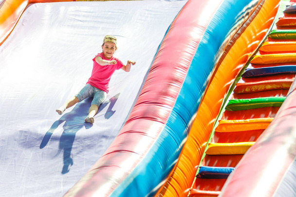Feliz niña teniendo un montón de diversión en un castillo de salto durante el deslizamiento - Foto, Imagen