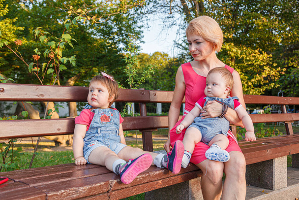 bela mãe com sua filha e filho estão sentados em um banco no parque no verão close-up - Foto, Imagem