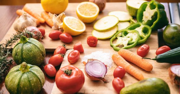 Organikus friss zöldség háttér. Biocukkini, répa, paradicsom, paprika, avokádó és hagyma a konyhaasztalon. Egészséges ételek, vegetáriánus konyha. - Fotó, kép