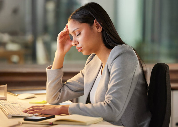 Girato di una giovane donna d'affari che sembra stressata mentre usa un computer alla sua scrivania in un ufficio moderno. - Foto, immagini