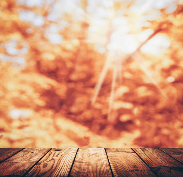 Autumn, fall, Thanksgiving concept.  table and autumn nature. Warm day. Empty wooden table and autumn leaves over blurred nature background. Fall background with empty space for product display. - 写真・画像
