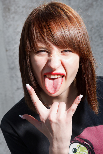 Close up portrait of cool young girl showing her tongue and rock - Foto, afbeelding