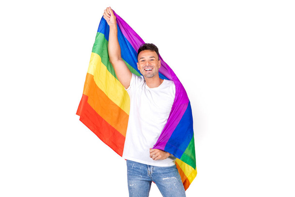 Πορτρέτο ενός χαμογελαστού νεαρού ομοφυλόφιλου που κρατά μια σημαία lgbtqi απομονωμένη σε λευκό φόντο - Φωτογραφία, εικόνα