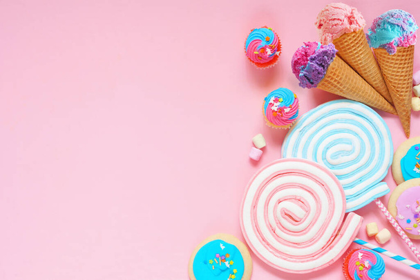 Pastellfarbene Bonbons Seitenrand. Eis, Kekse, Cupcakes und eine Auswahl an Leckereien. Blick über einen rosafarbenen Hintergrund. Kopierraum. - Foto, Bild