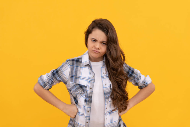 angry teen child in checkered shirt with long curly hair on yellow background. - Fotografie, Obrázek