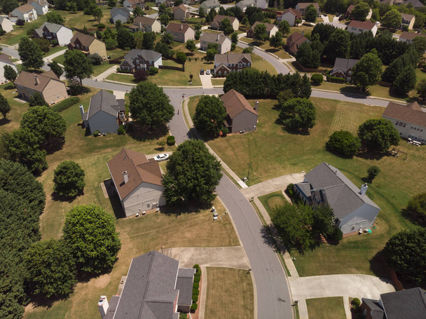 Vista aérea panorámica de un suburbio con hermosas casas y césped cuidado disparado durante un día soleado en verano de 2022 - Foto, imagen