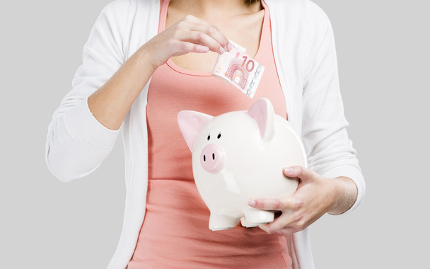Blonde woman with a piggy bank - Фото, зображення