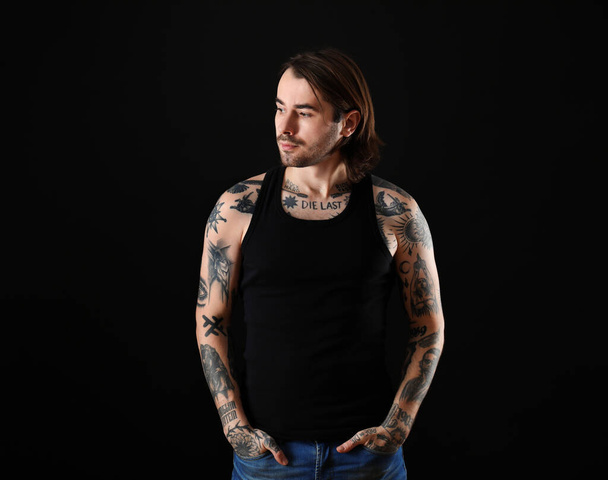 Young man with tattoos on body against black background - Фото, изображение