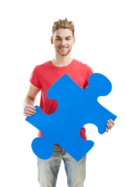 Young man holding a puzzle piece - Photo, Image