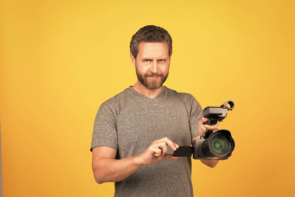Gülümseyen sakallı adam videograf kamera ve görüntü yönetmeni ile vlog için film yapıyor.. - Fotoğraf, Görsel