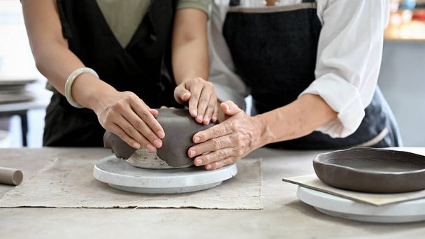 Oříznutý obraz, Ruce vyrábějící hliněnou keramiku, formující hliněnou keramiku v dílně. Ruční práce, ruční kuchyňské nádobí. - Fotografie, Obrázek