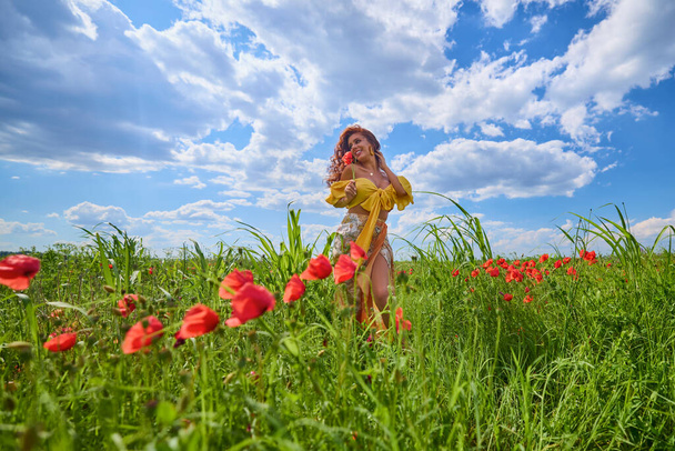 Mujer atractiva en un campo de amapola con flores en plena floración. - Foto, Imagen
