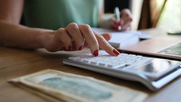 Close-up of woman doing calculation of expenses and income and making notes. Project profitability, debit and credit and accounting concept - Photo, Image