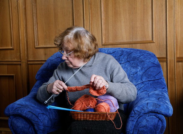 The old woman sits in an armchair and knits - Fotoğraf, Görsel