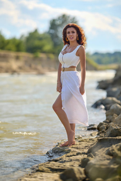 Belle femme en robe blanche sur la rive d'une rivière en été. - Photo, image