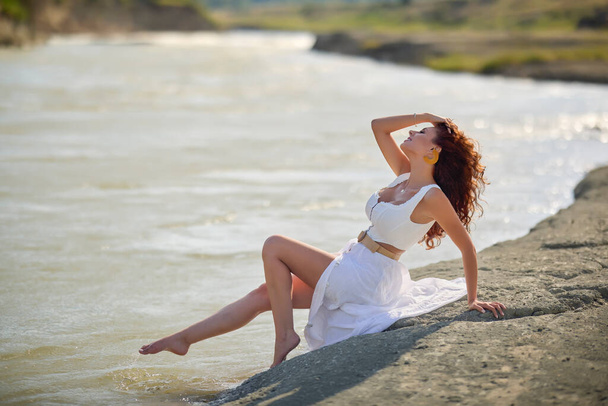 Mulher bonita em vestido branco na margem de um rio no verão. - Foto, Imagem