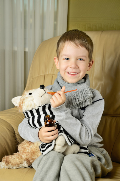 little boy feeds medicinal syrup the toy dog and looking at came - Foto, imagen