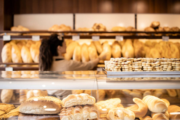 Close up view of tasty and delicious cookies in bakery shop and worker arranging pastry in background. - Foto, Imagen