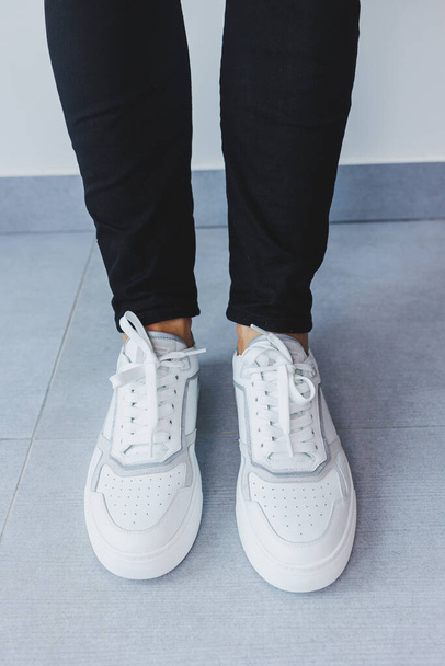 Un uomo in pelle bianca sneakers casual, sneakers da uomo estive. Uomo in jeans neri - Foto, immagini