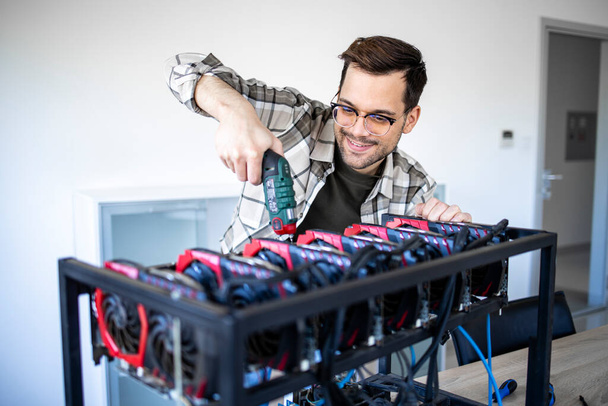 An intelligent caucasian man using screwdriver to build cryptocyrrency bitcoin rig for mining. - Photo, Image
