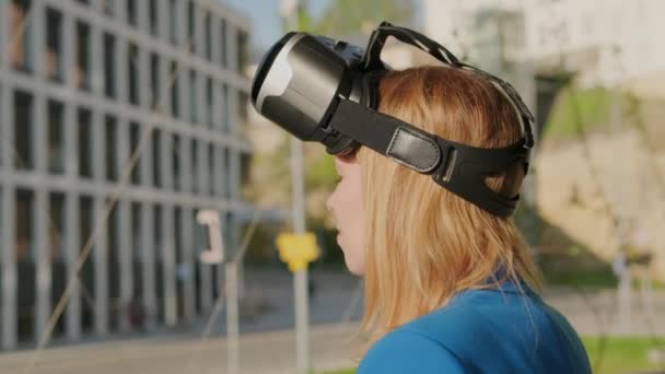 Woman wearing virtual reality headset and start to use virtual interface near business center - Πλάνα, βίντεο