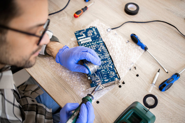 Een expert die elektronisch apparaat repareert en moederbord soldeert in de computerservice. - Foto, afbeelding