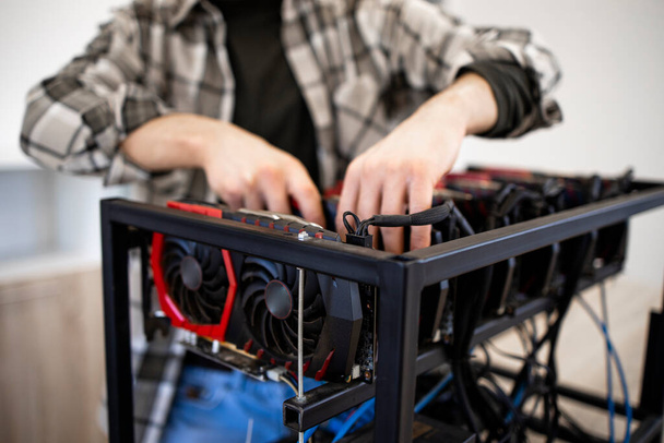 Unrecognizable person or an expert building new mining rig for bitcoin cryptocurrency. Blockchain technology and graphic cards in row. - Photo, Image