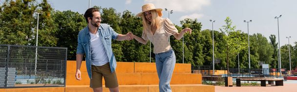 Homme souriant tenant la main de la petite amie dans le skate park, bannière  - Photo, image