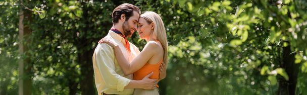 Πλευρική άποψη του trendy ρομαντικό ζευγάρι αγκαλιάζει στο πάρκο καλοκαίρι, πανό  - Φωτογραφία, εικόνα