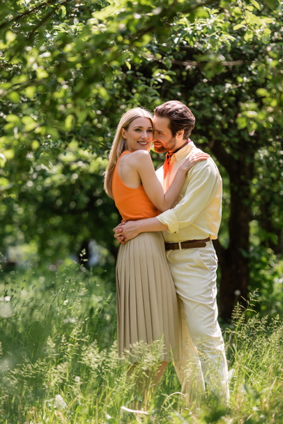 Stylish woman embracing boyfriend and looking at camera in summer park  - Valokuva, kuva